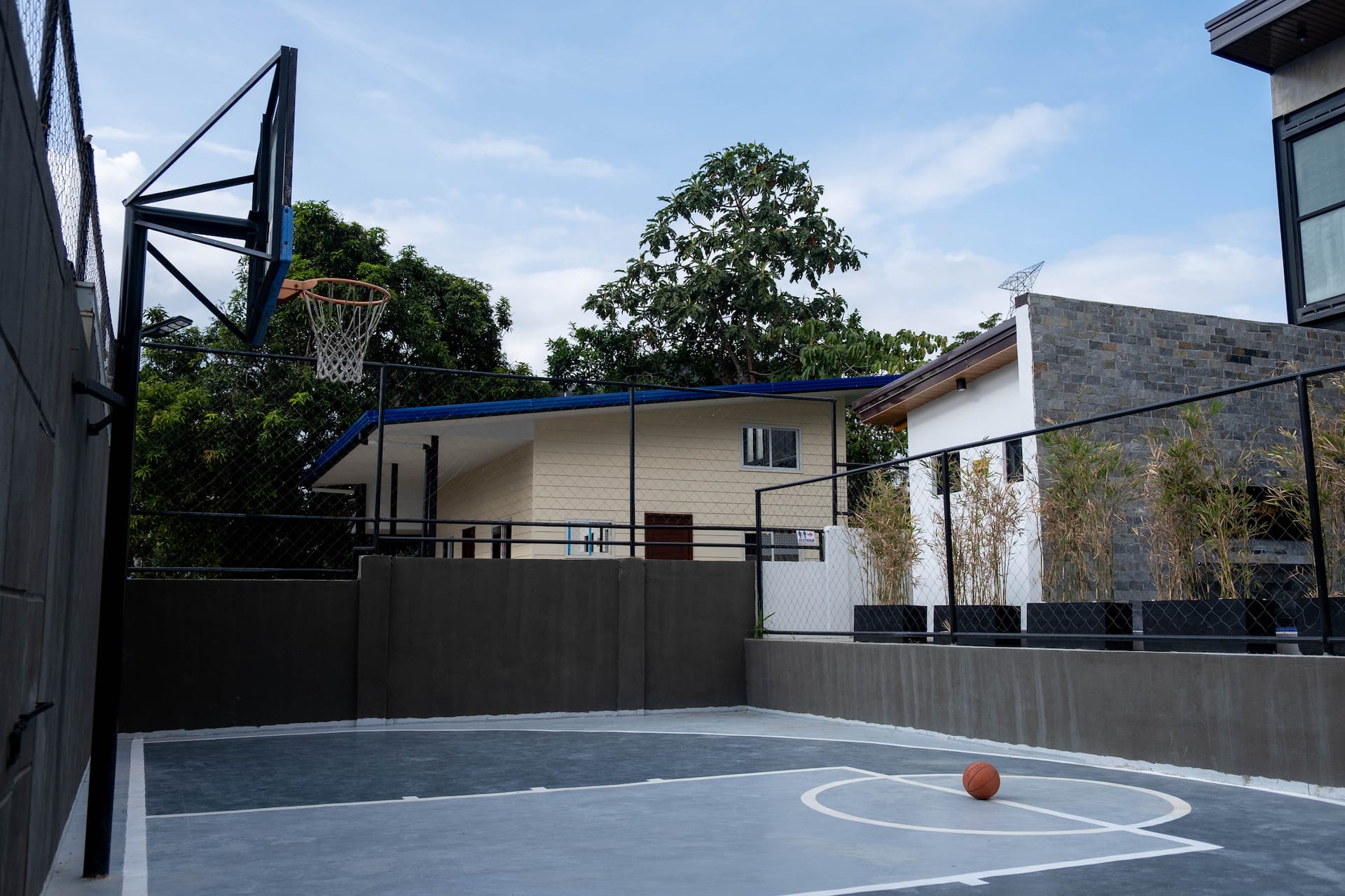 Outdoor Basketball Half-Court with Fenced Perimeter & Mountain Backdrop
